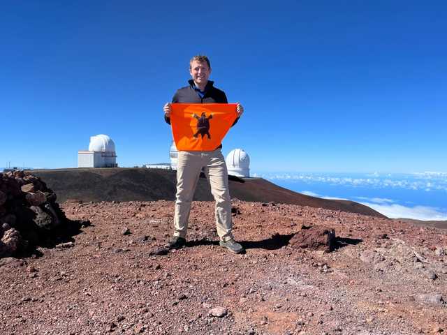 Red cinder at Mauna Kea's summit with observatory domes behind