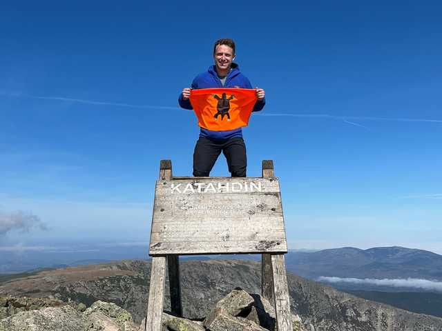 Weathered Katahdin summit sign, Justin standing on top of it