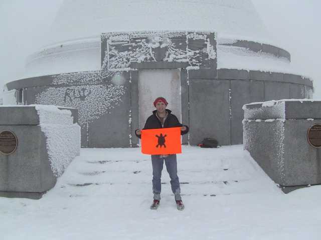 Frost-covered memorial tower on Mount Greylock, with Justin holding his orange turtle flag